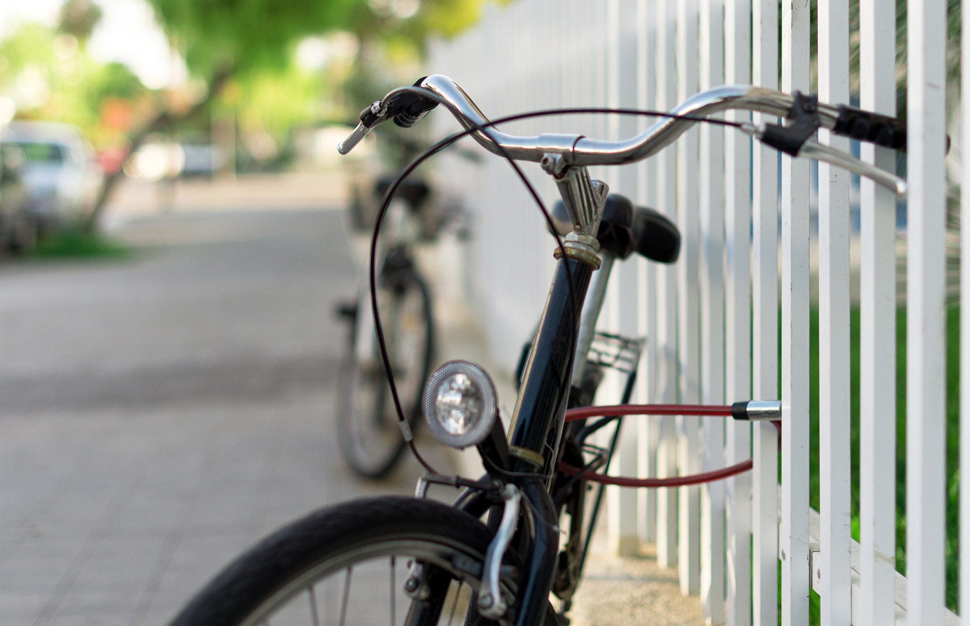 Bicycle chained up outdoors to a metal fence.