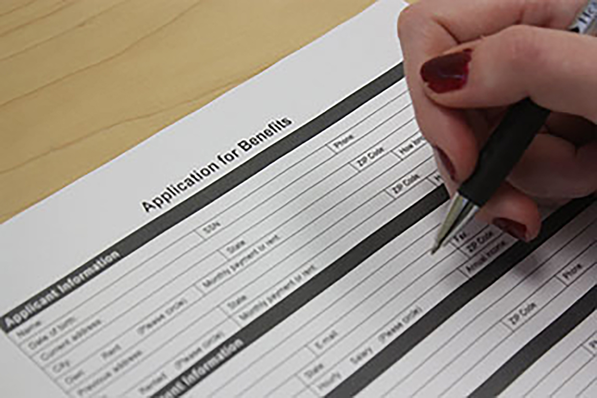 Close up of person filling out benefits application form.