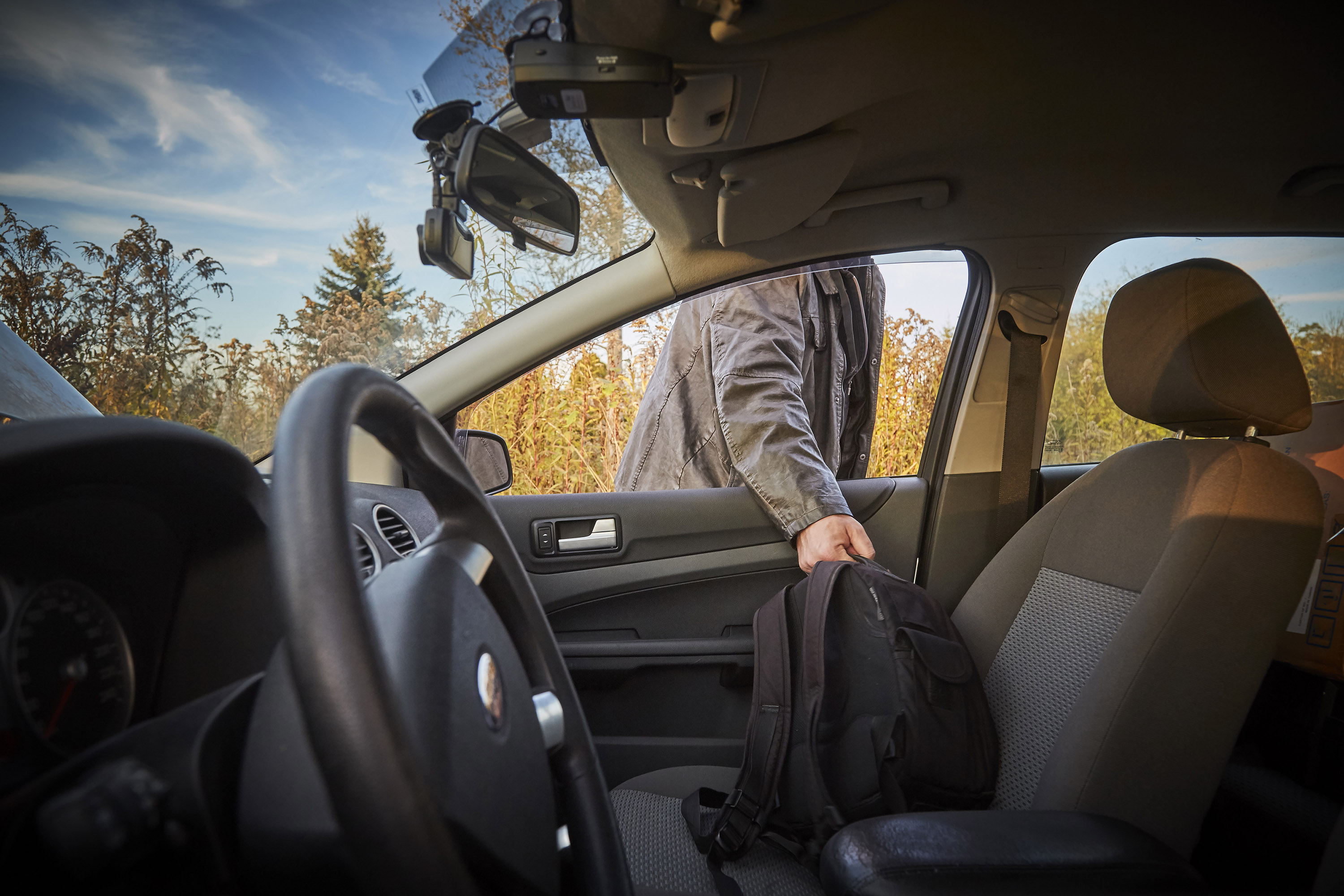 Person stealing backback out of an open car window.