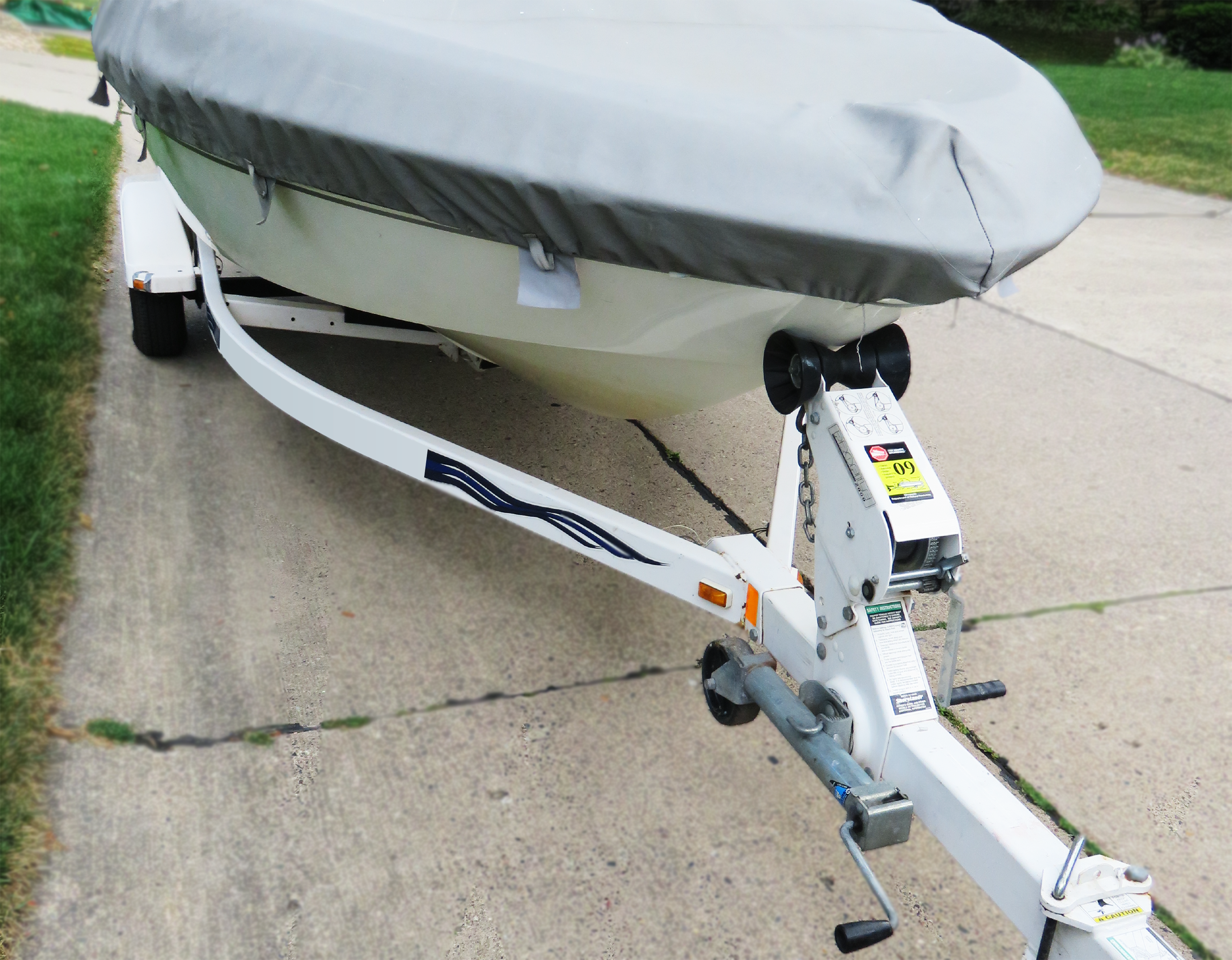 Small speedboat on a trailer being towed on a street.