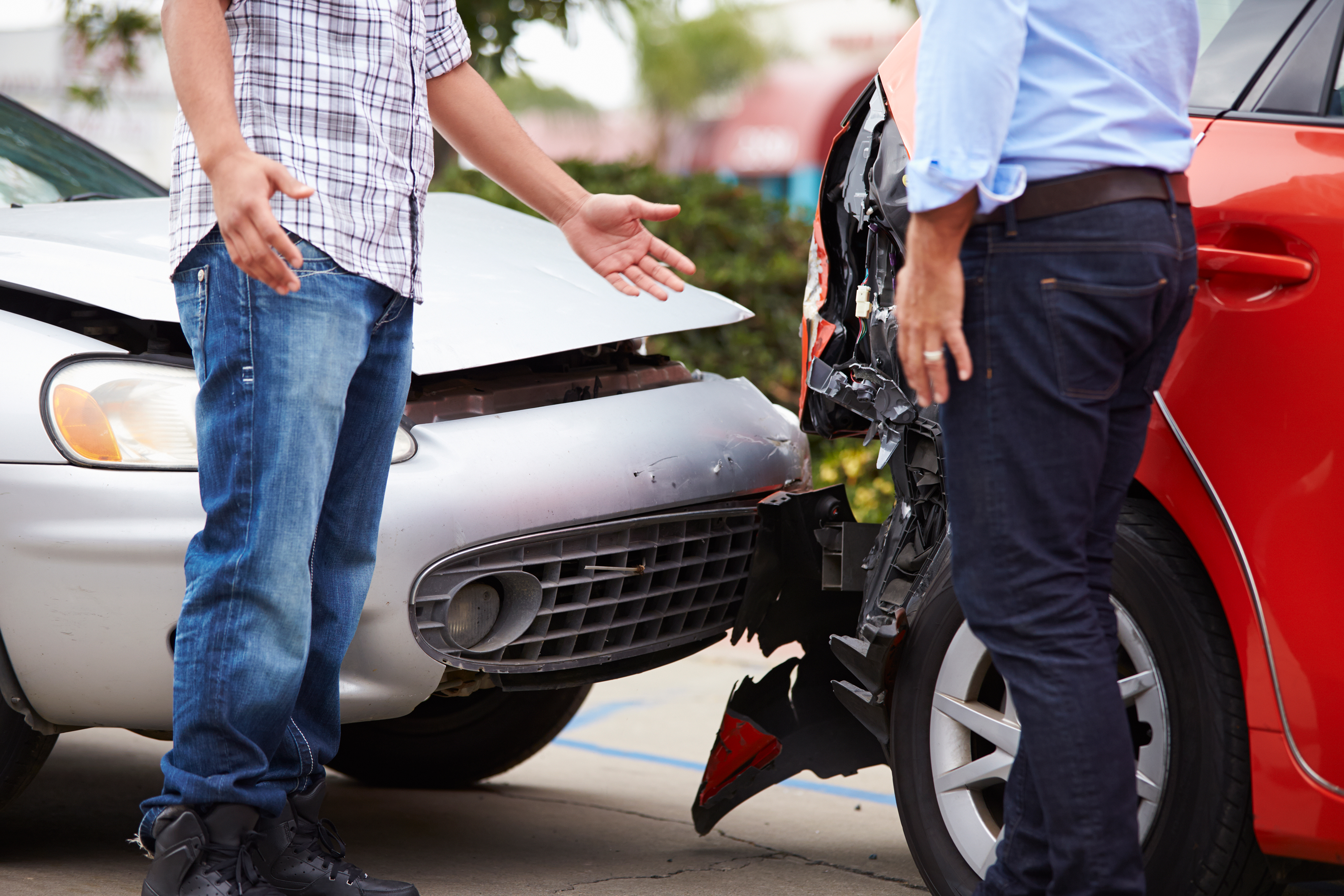 Two people standing at the scene of a car accident.